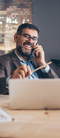 Businessman smiling while on the phone and looking at his laptop. 
